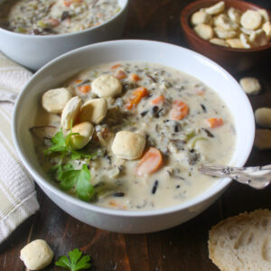 A bowl of Chicken Wild Rice Soup with carrots and topped with oyster crackers.