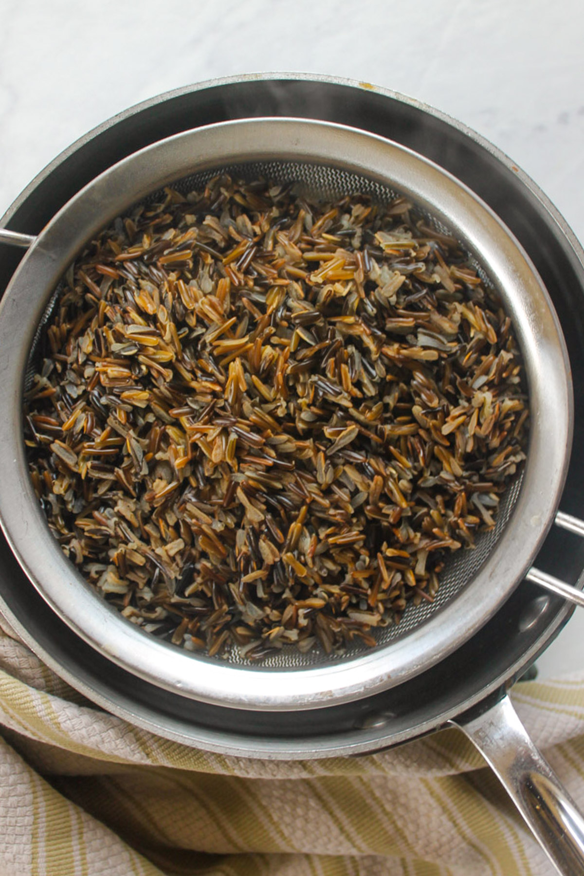 Wild rice cooked separately and sitting in a strainer to add to soup.