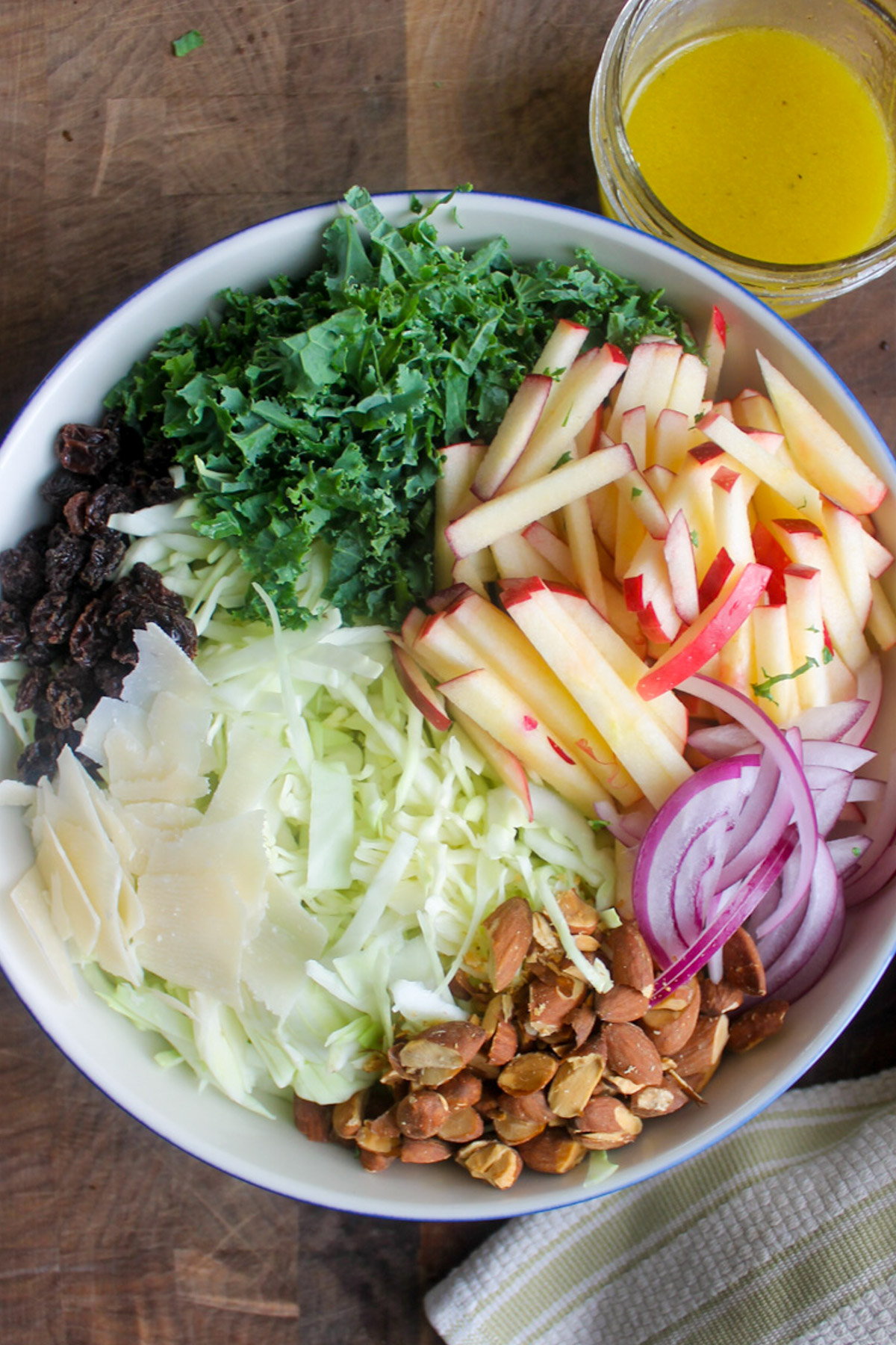 Adding all ingredients to a bowl of kale apple slaw.