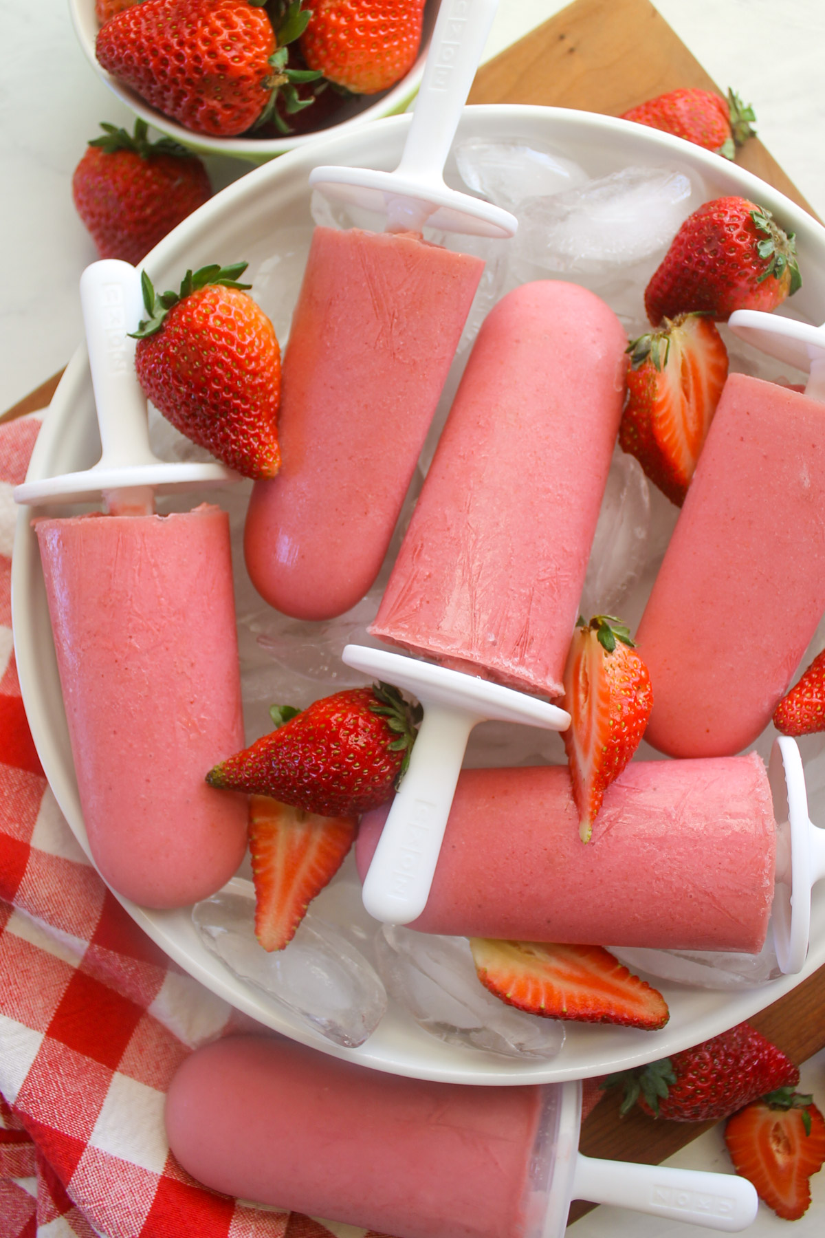 Frozen yogurt strawberry popsicles and fresh strawberries.