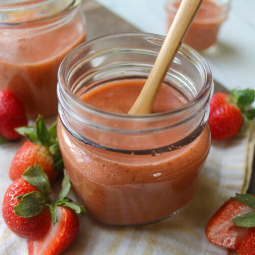 A few jars of strawberry rhubarb freezer sauce with a spoon.