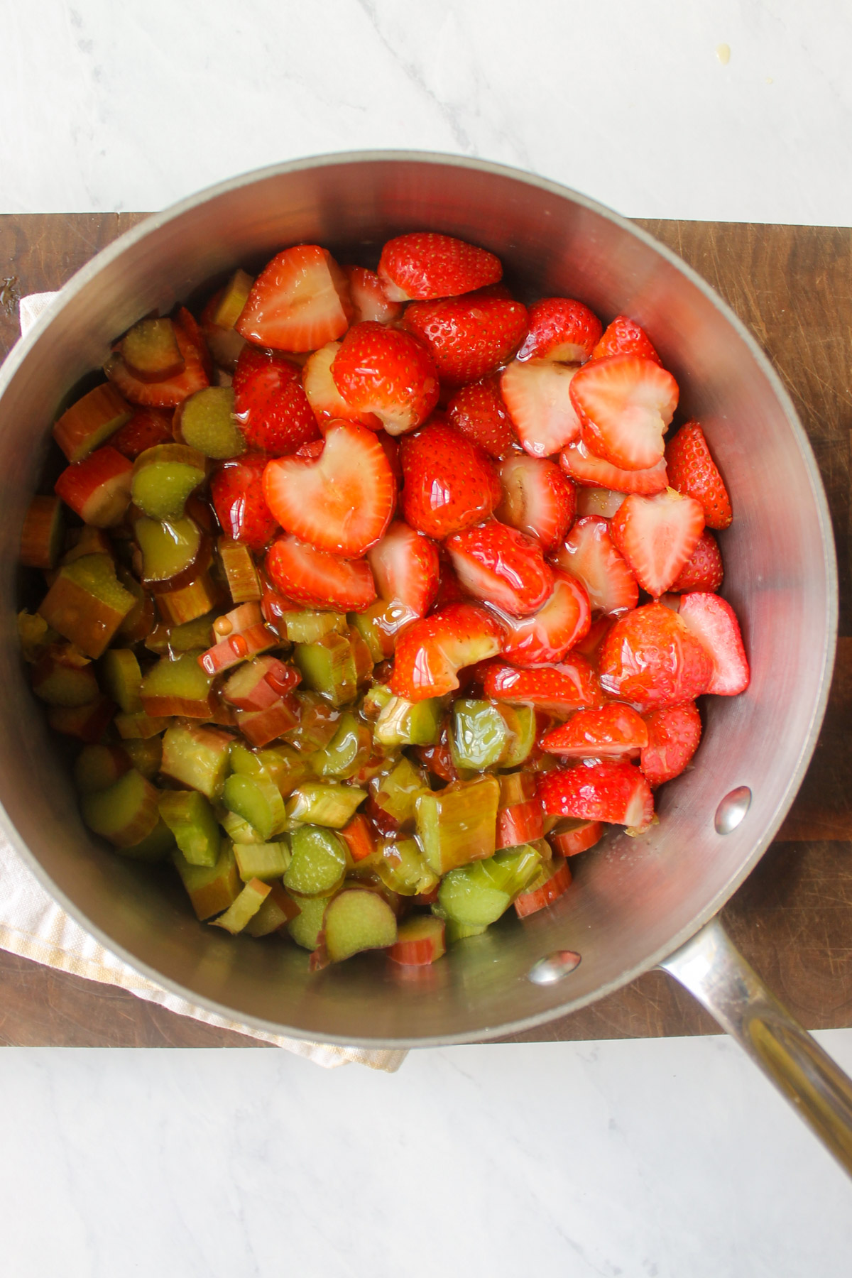 Strawberries, rhubarb, honey and orange juice in a sauce pan.