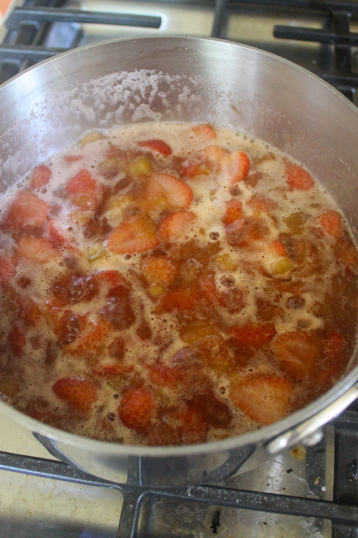 Strawberry Rhubarb Sauce simmering in a pot on the stove.