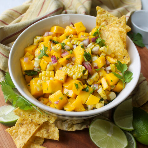 A bowl of mango sweet corn salsa with chips.