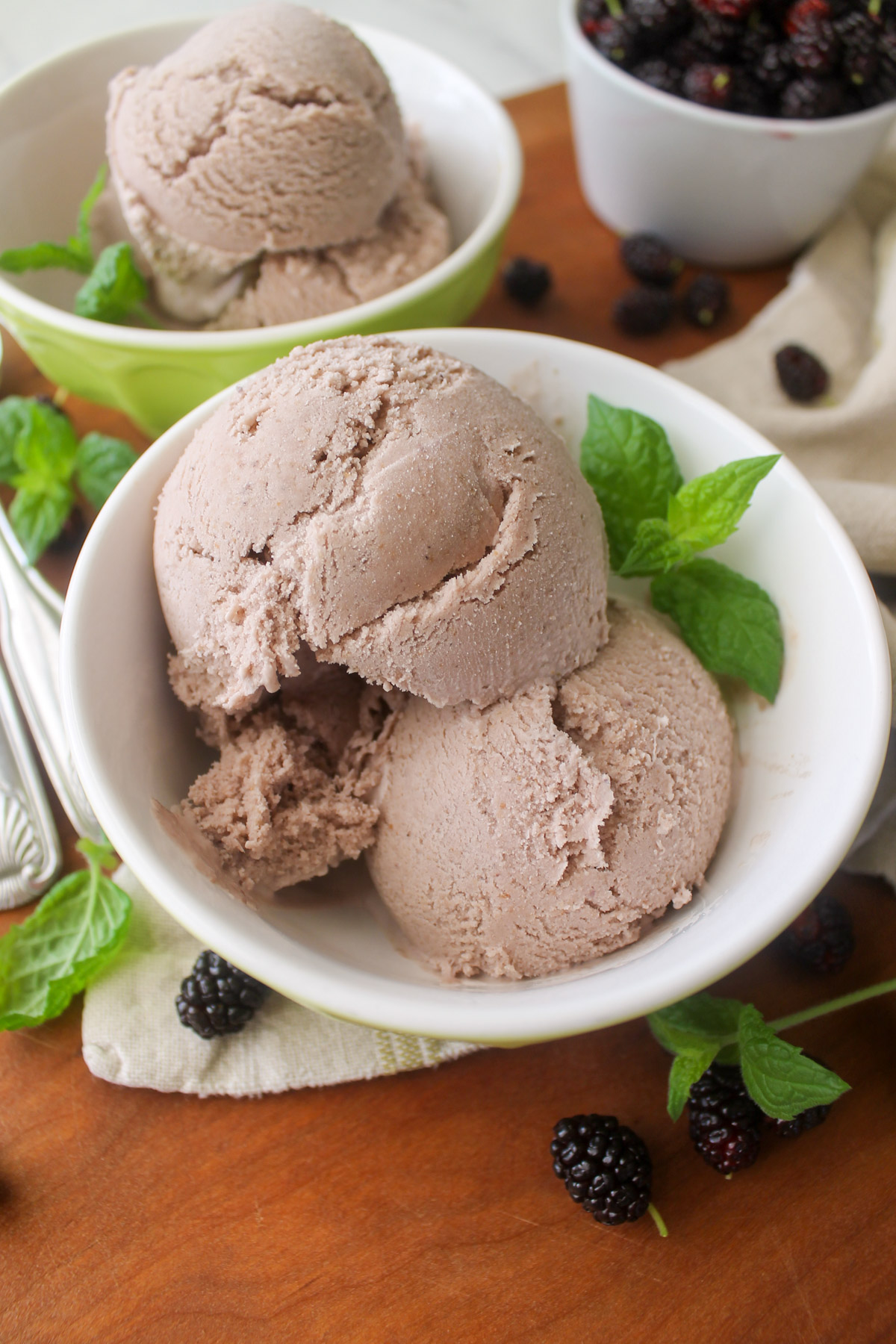 A bowl of scooped mulberry ice cream with mint leaves.