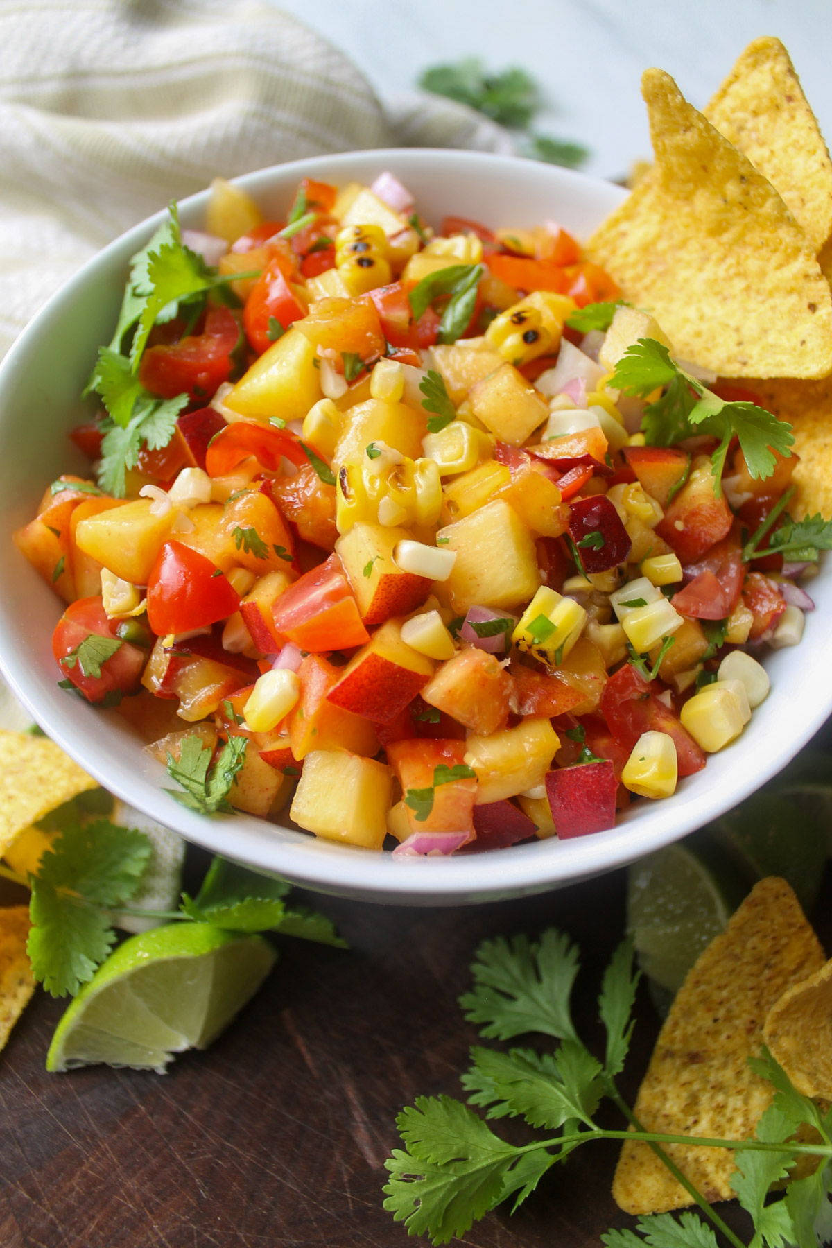 Corn and peach salsa with tortilla chips and lime wedges.