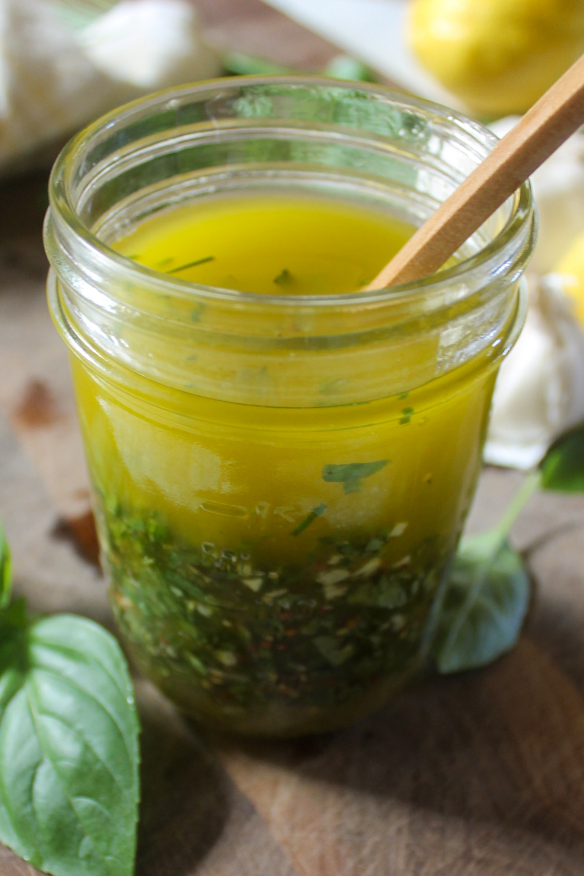 A jar of lemon herb dressing with lots of chopped fresh herbs.