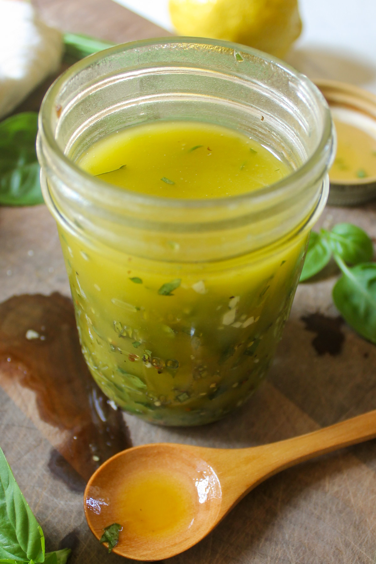 A jar of Lemon Herb Salad Dressing with a wooden spoon.