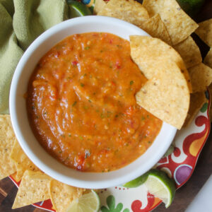 A bowl of peach tomato salsa with tortilla chips.