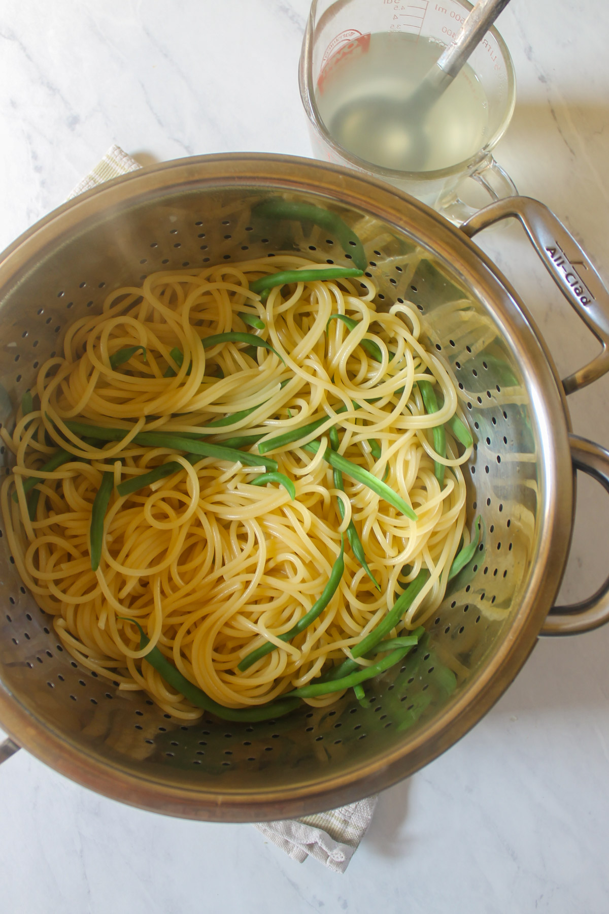 Spaghetti and green beans drained in a colander.