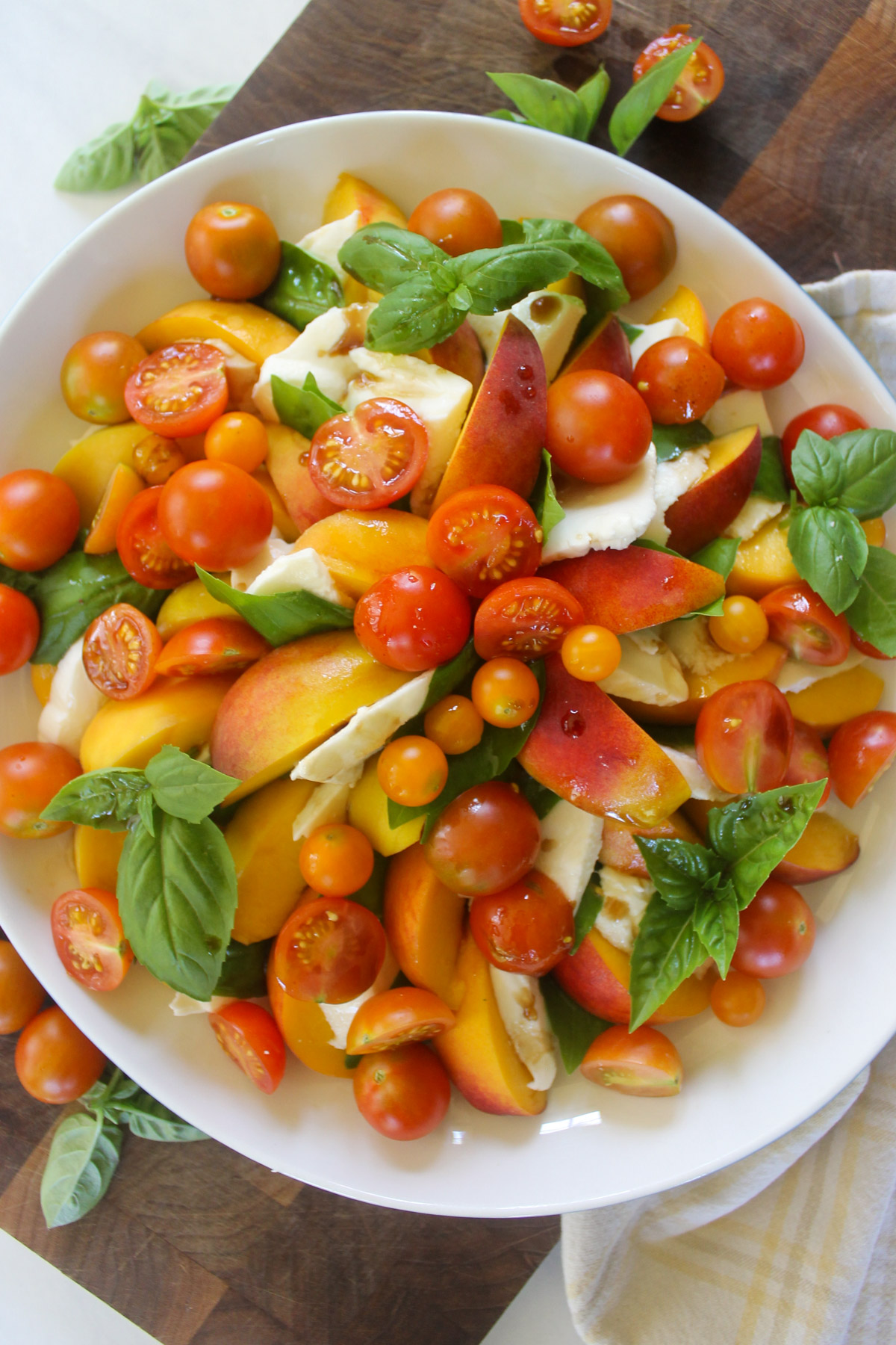 A platter of peach caprese salad with cherry tomatoes.