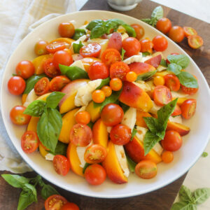 Peach Caprese Salad topped with cherry tomatoes and basil.