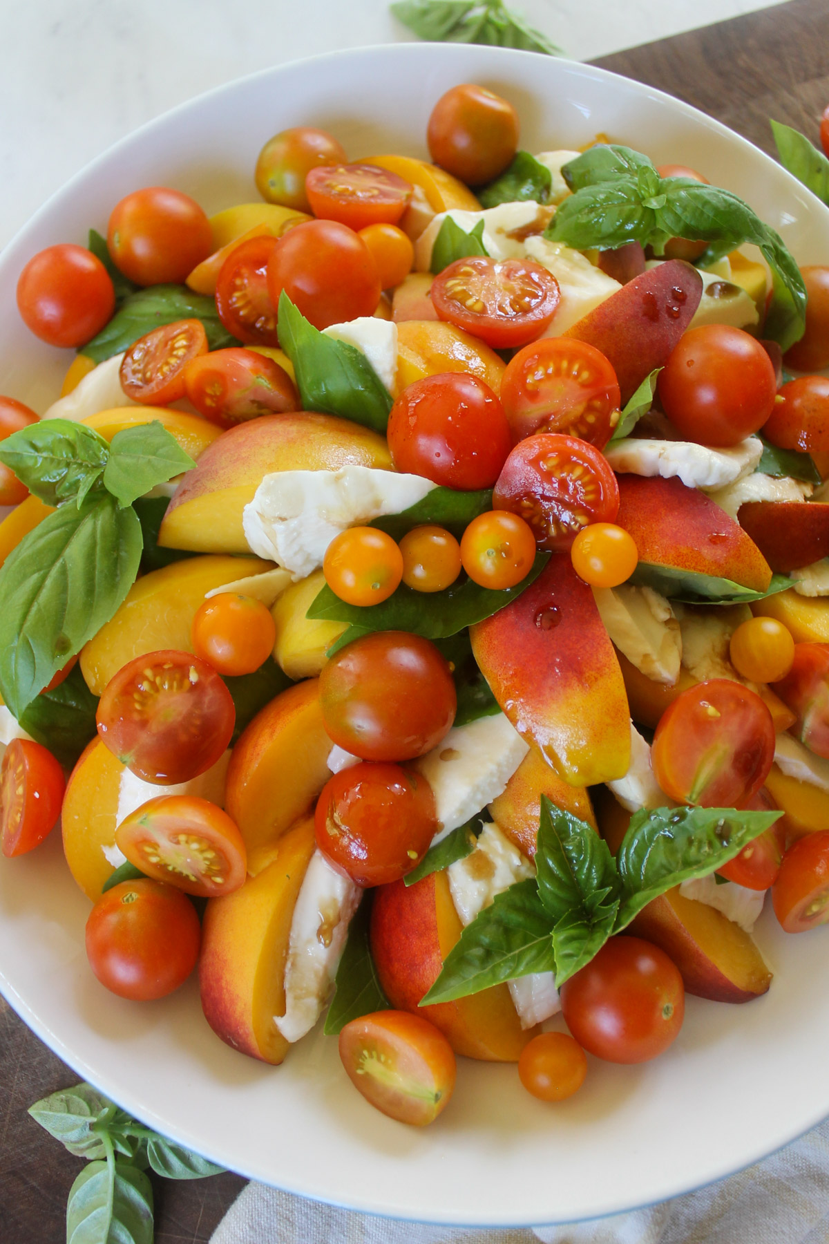 Peach Caprese Salad on a platter with garden tomatoes.