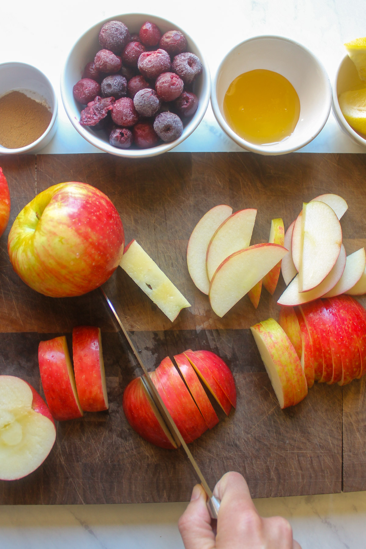 Thinly slicing apples on a cutting board.