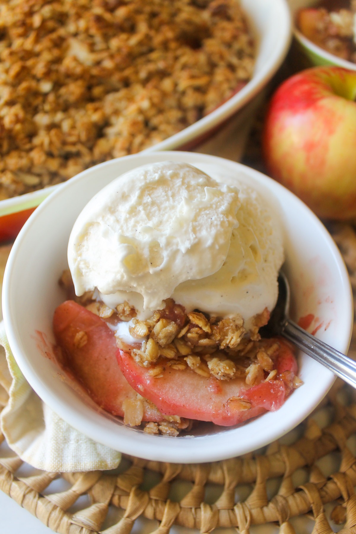 A small bowl of cherry apple crisp with vanilla ice cream.