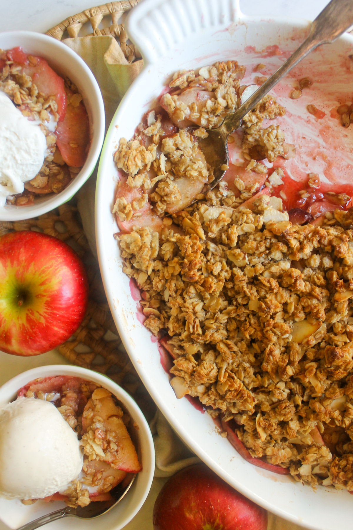 A pan of Apple Cherry Crisp scooped into 2 bowls with ice cream.