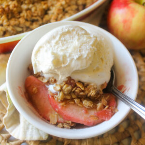 A bowl of cherry apple crisp topped with vanilla ice cream.