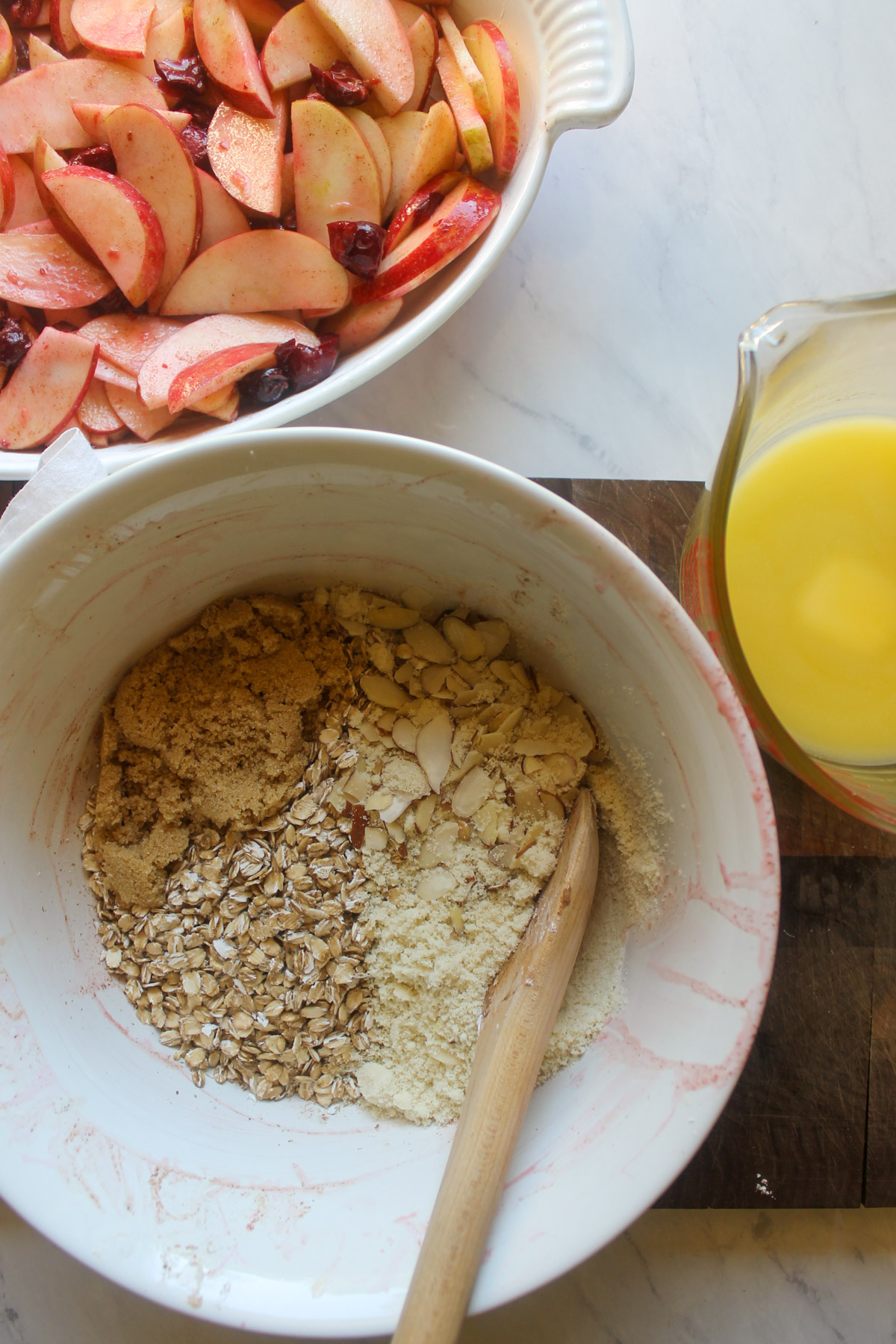 Mixing apple cherry crisp topping in a bowl next to melted butter.