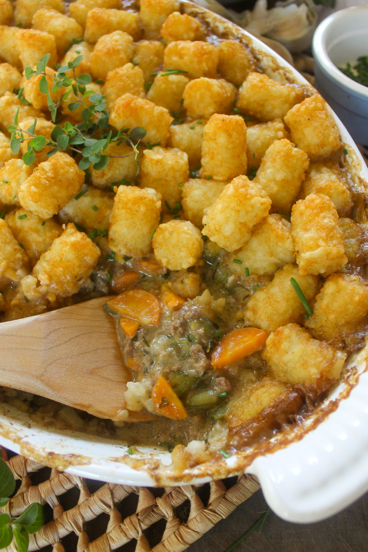 Tater tot casserole with a wooden spoon.