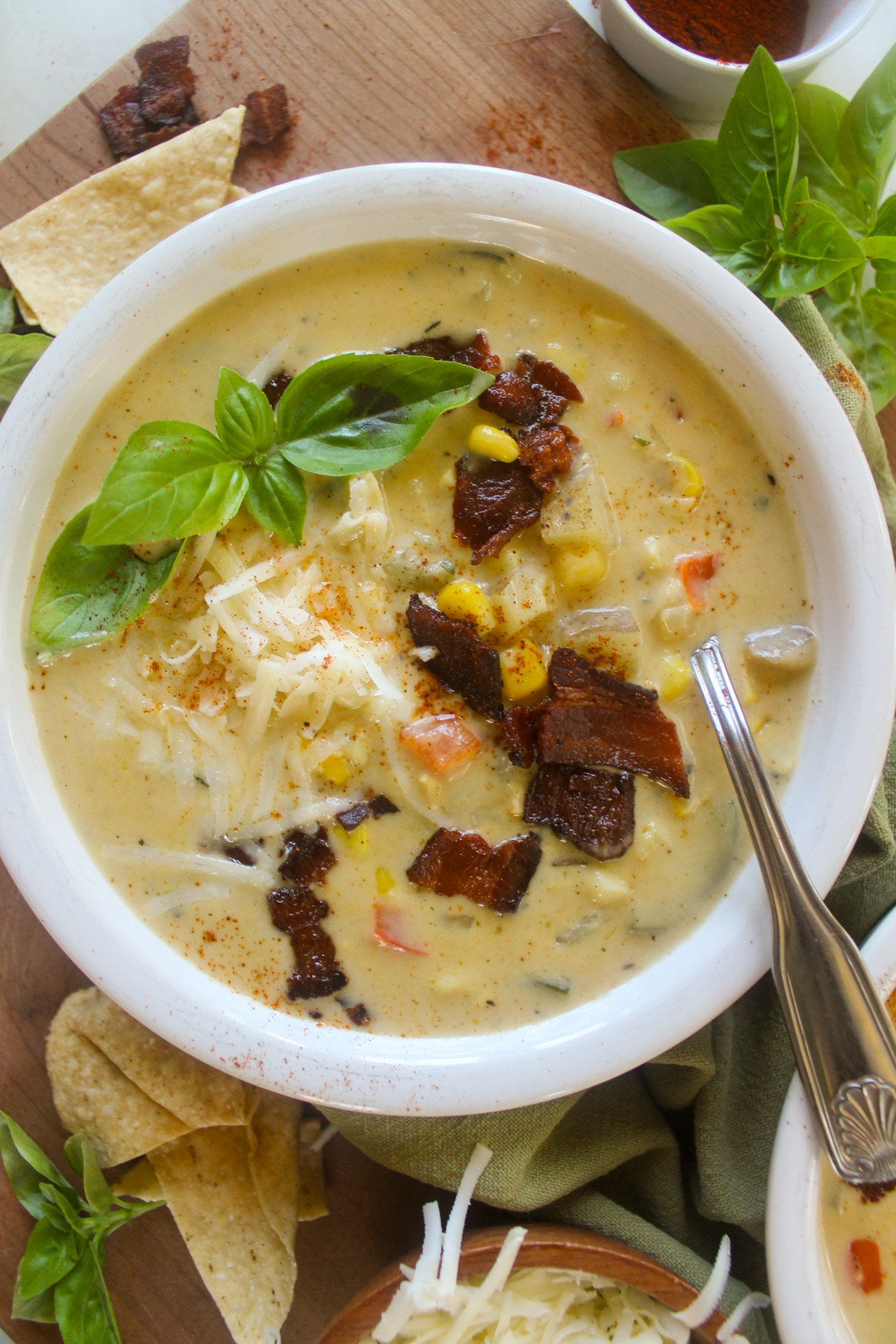 A bowl of Zucchini Corn Chowder with corn kernels, bacon, cheese and basil.