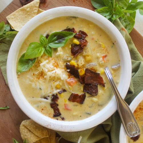 A bowl of yellow Zucchini Corn Chowder soup with white cheddar cheese.