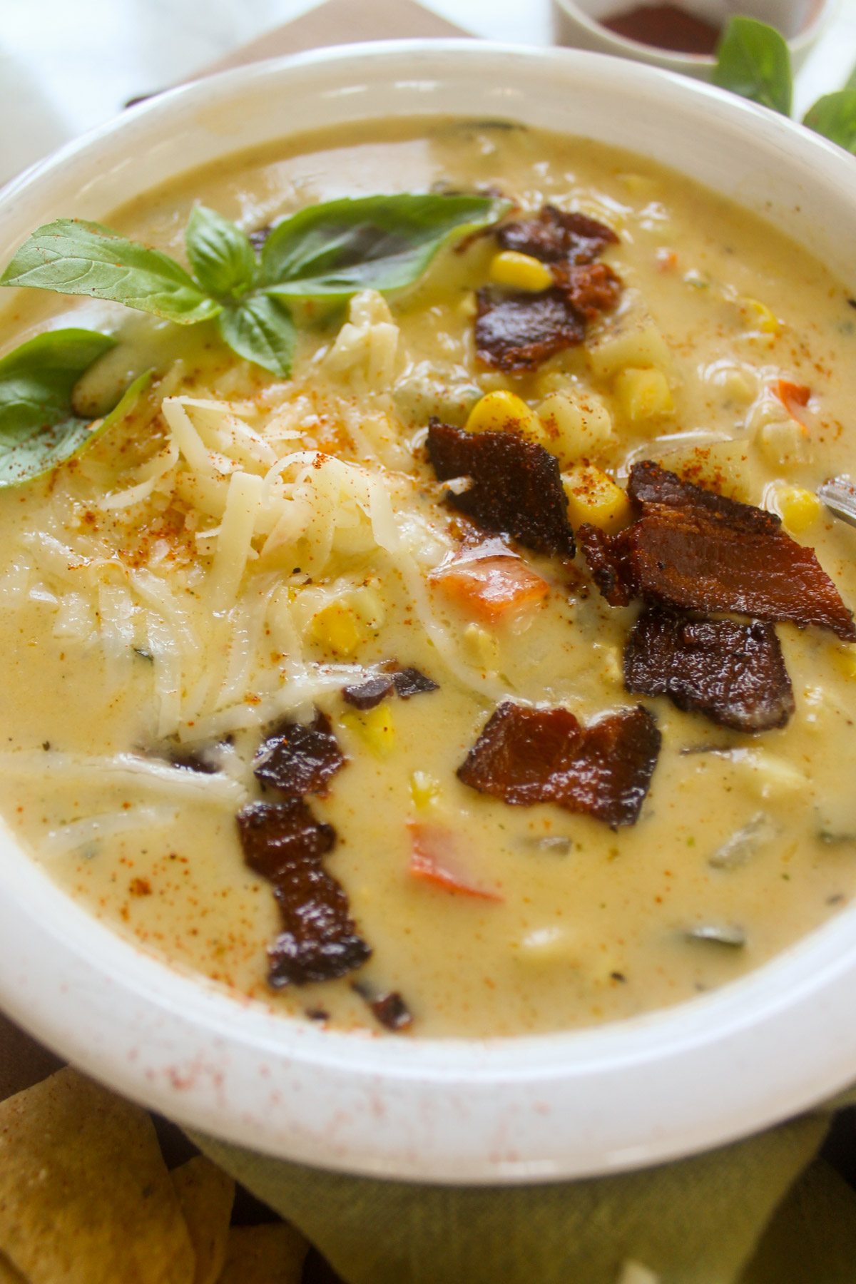 A white bowl of Zucchini Corn Chowder with bacon.