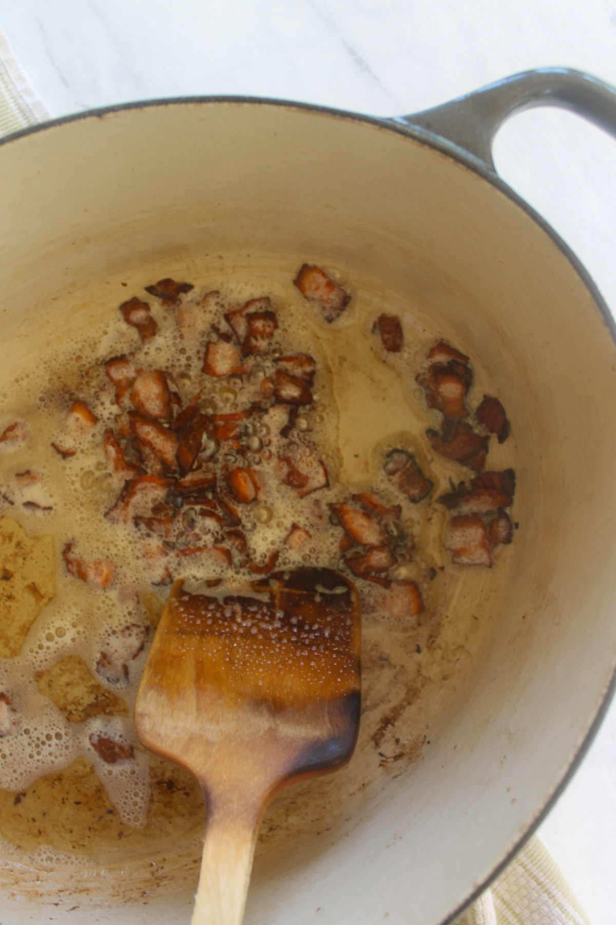 Cooking chopped bacon in a soup pot.