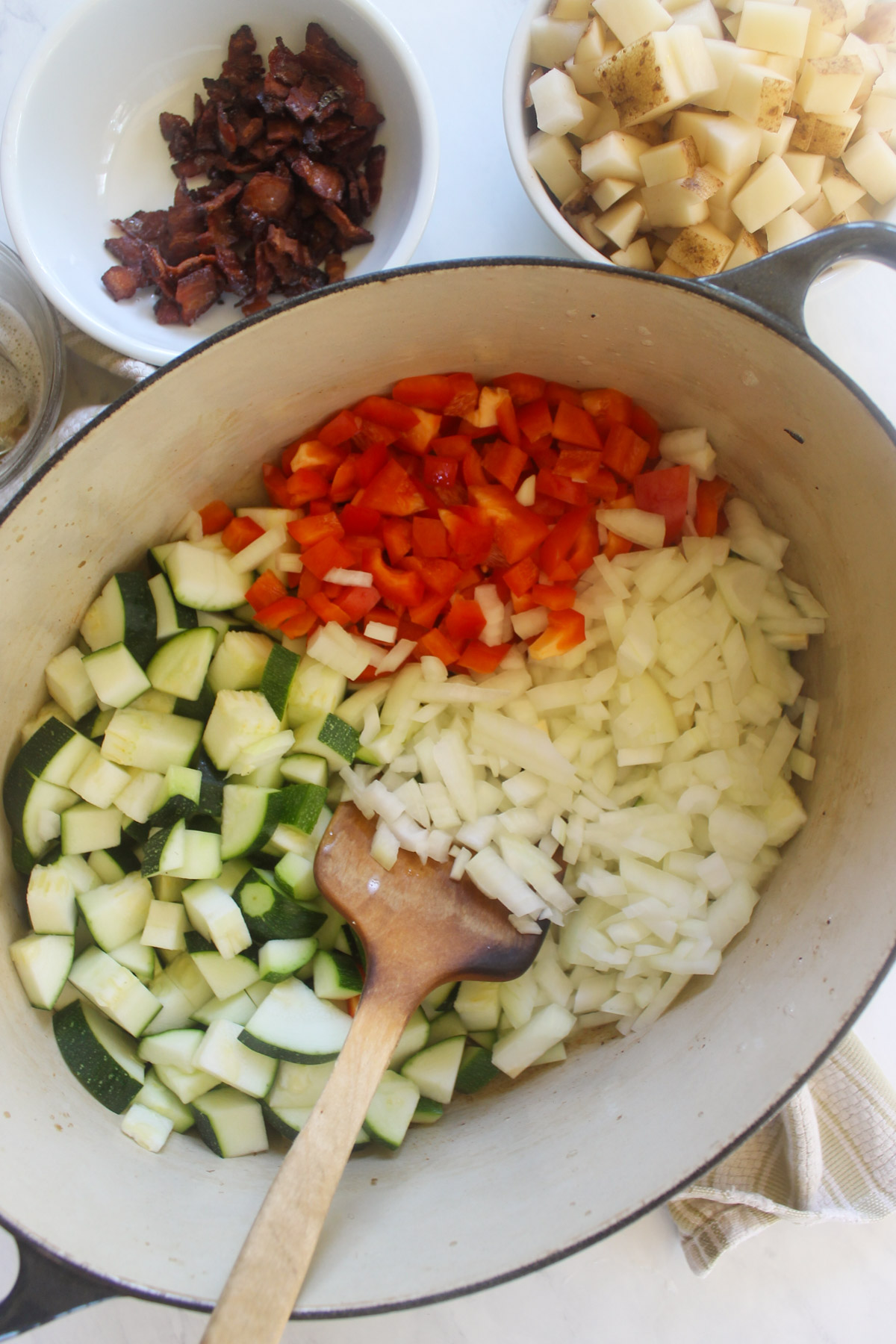 Sautéing onion, zucchini, and red pepper in a soup pot.