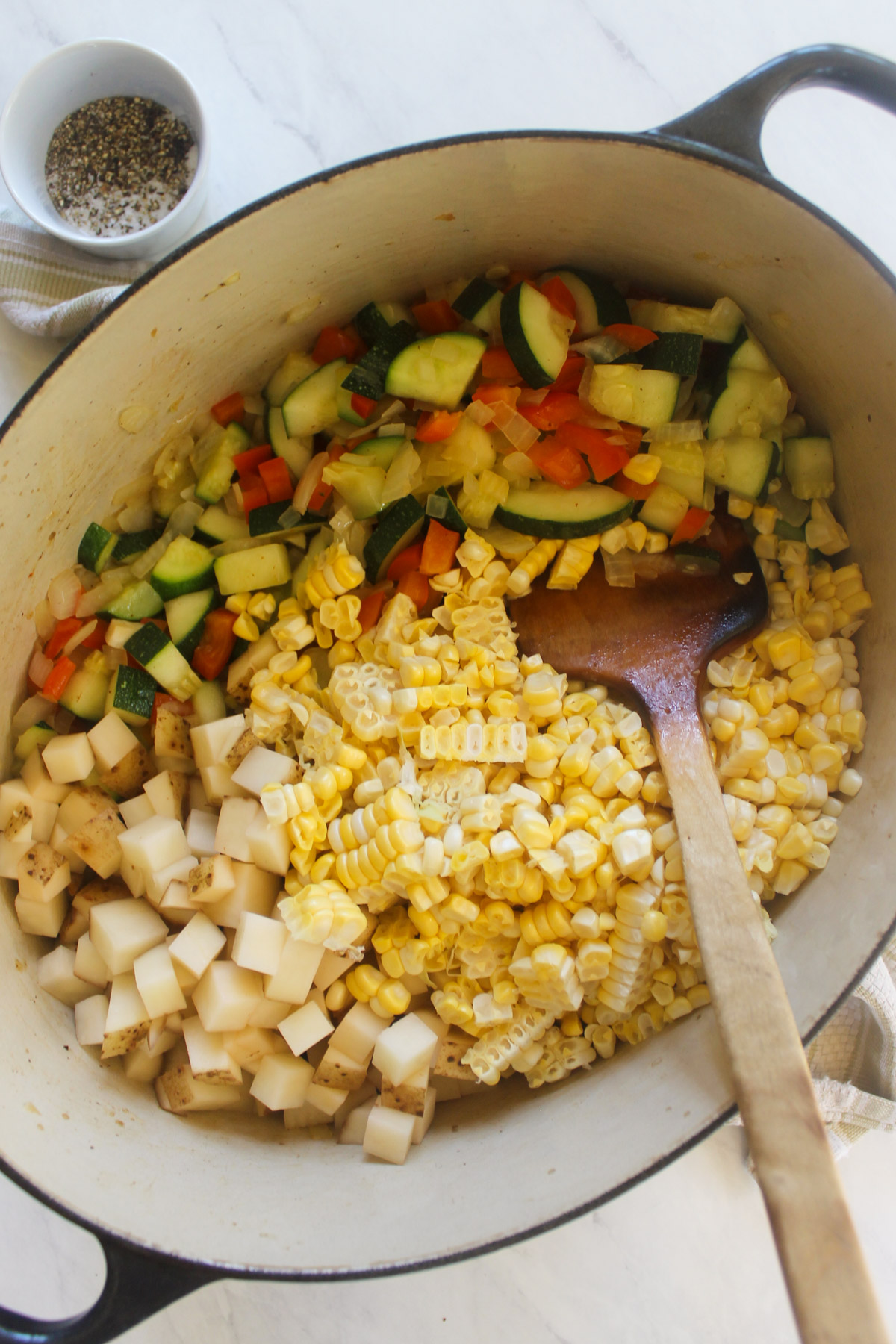 Adding corn and potatoes to sautéed zucchini, onion and bell pepper.