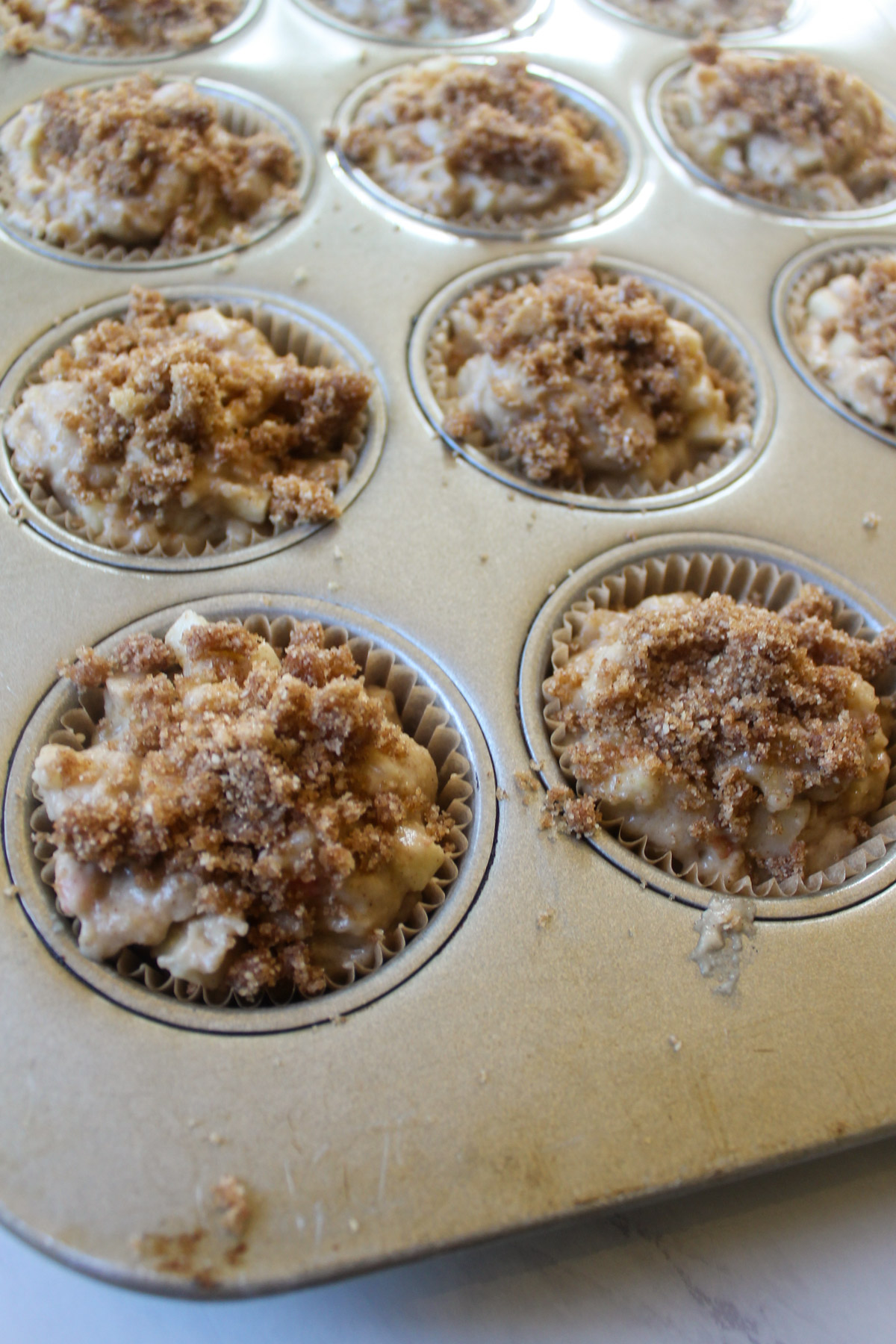 Apple muffin batter in muffins cups.