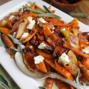 A platter of roasted carrots and apples with bacon and feta cheese.