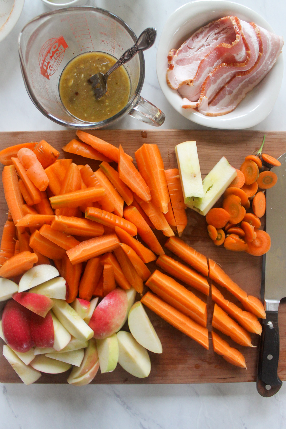 Sliced carrots and apples on a cutting board.