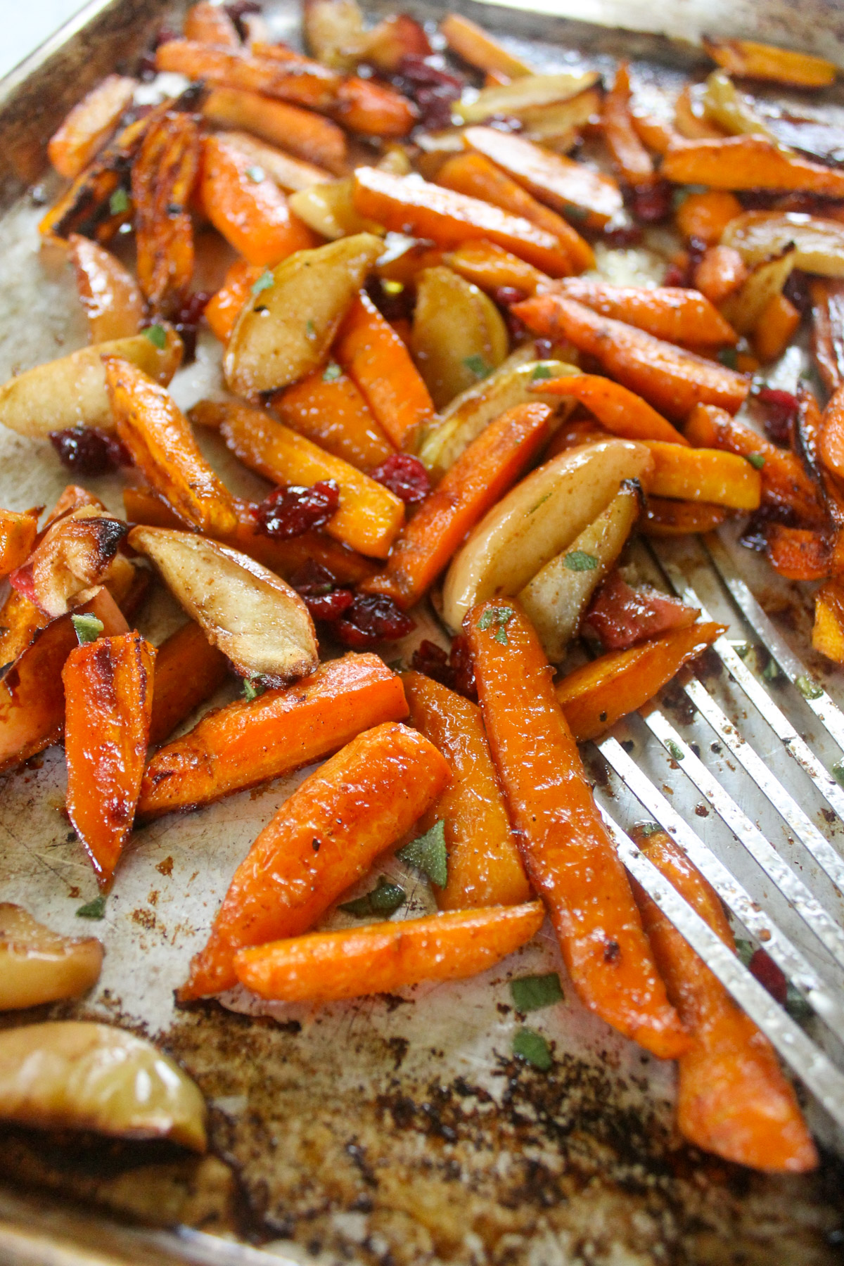 Roasted carrots and apples on a sheet pan with dried cranberries.