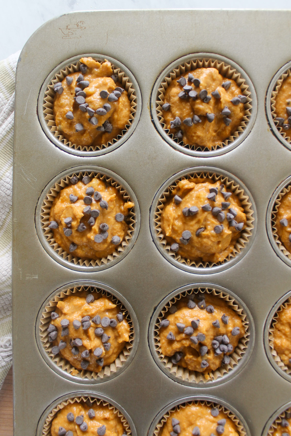 Muffin cups filled with pumpkin batter and mini chocolate chips.