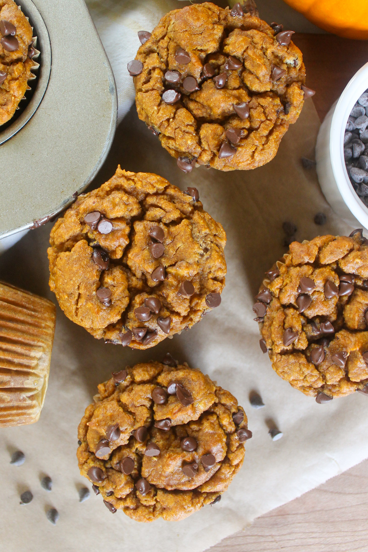 Pumpkin muffins next to a bowl of mini chocolate chips.