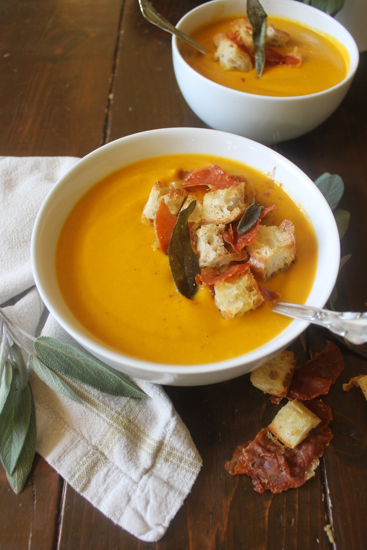 Bowls of pumpkin sweet potato soup with croutons, crispy prosciutto and sage.