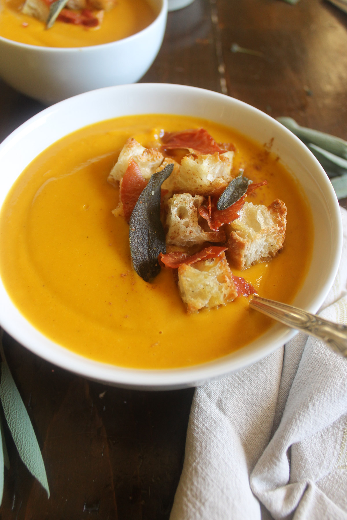 Sweet potato pumpkin soup bowls with croutons and sage.