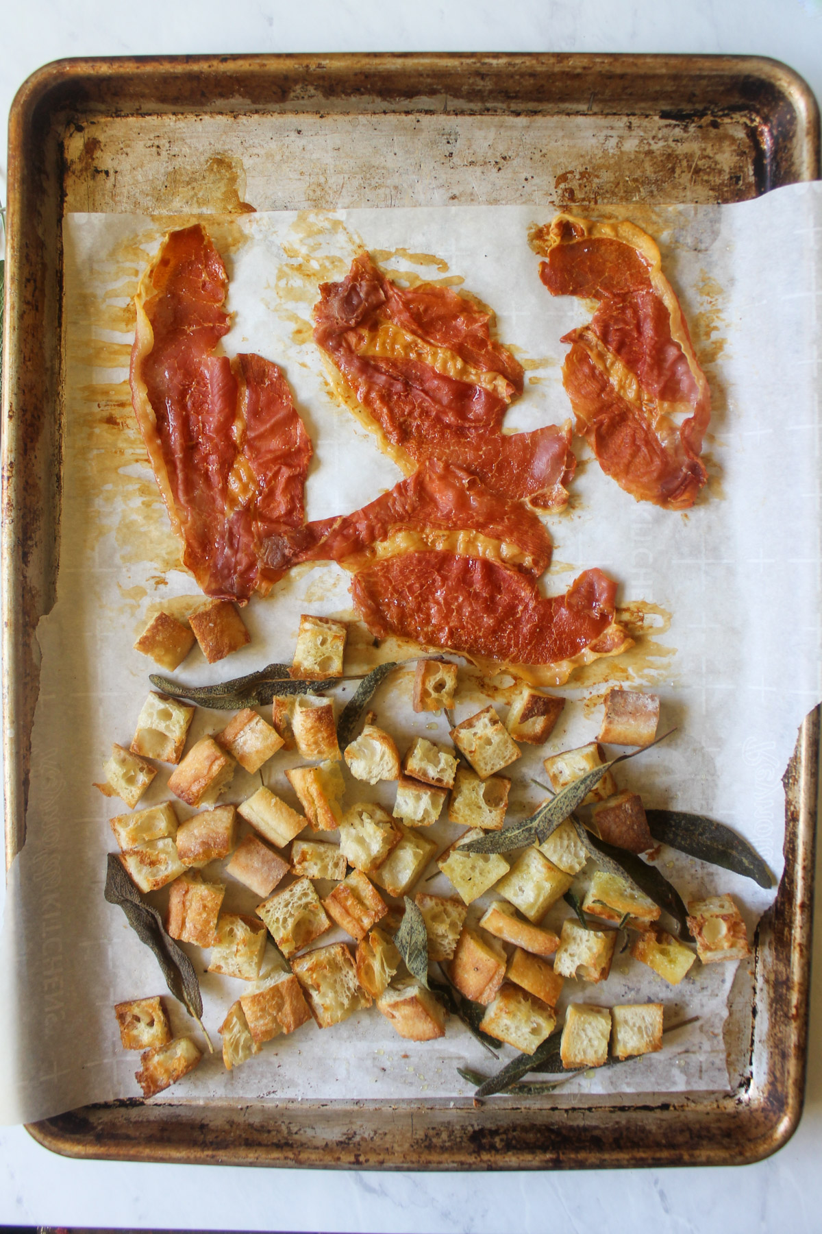 Baked crispy prosciutto and croutons on a sheet pan.