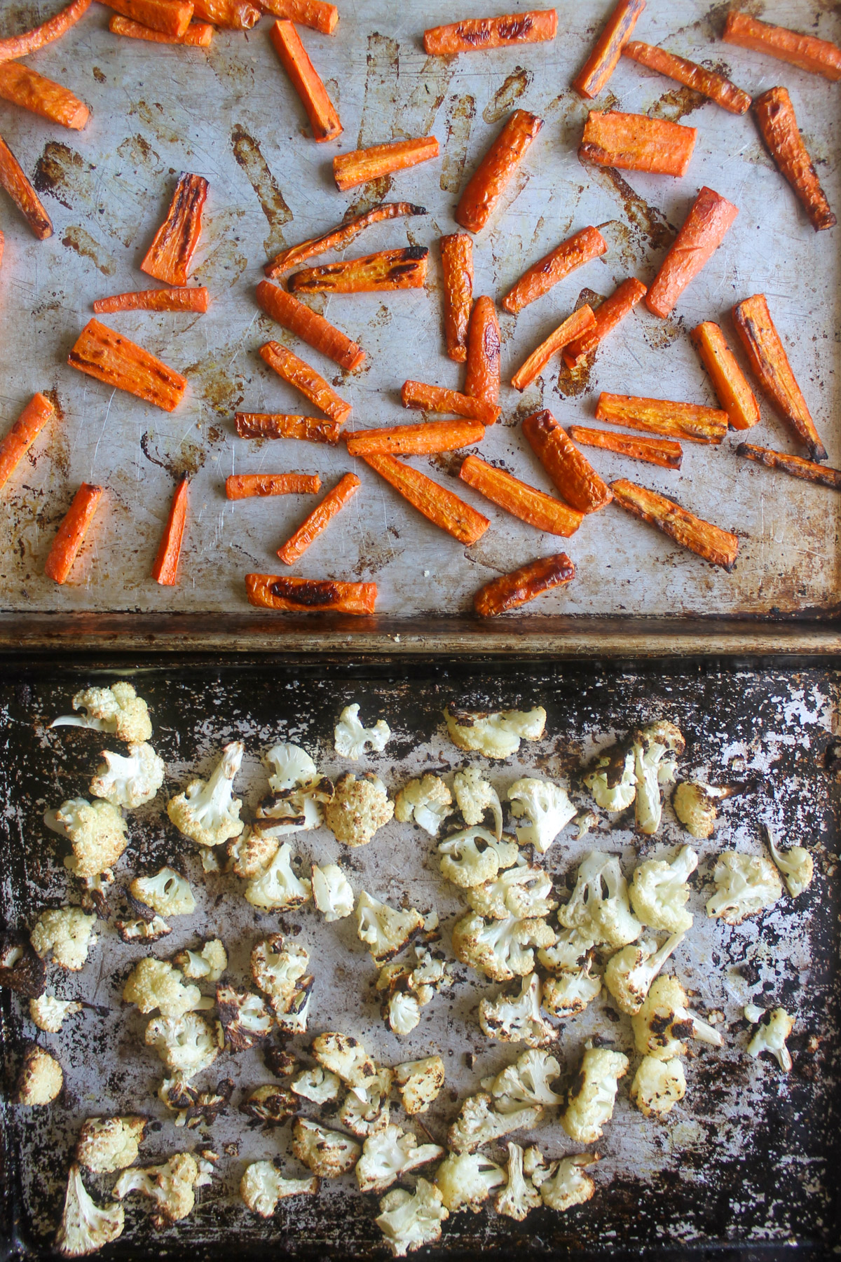 Roasted carrots and cauliflower on two large sheet pans.