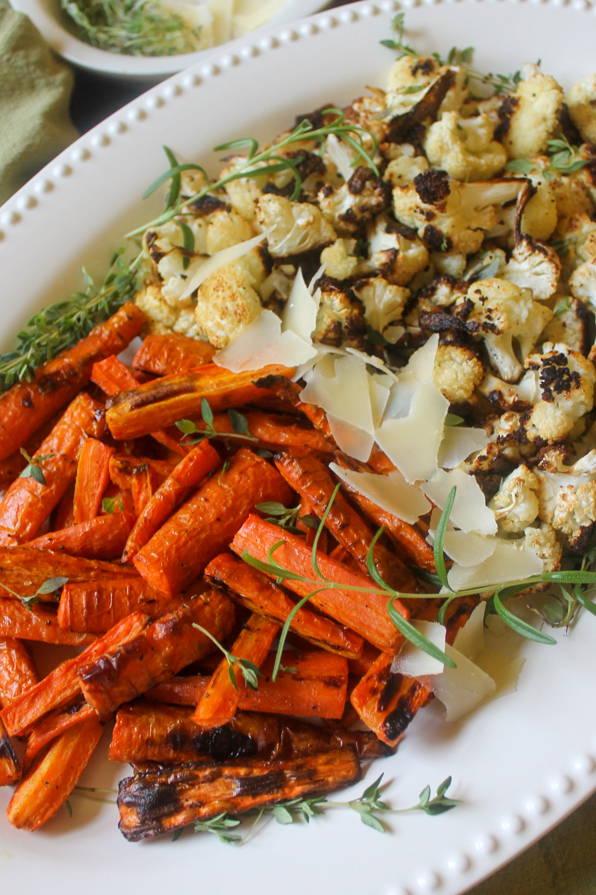 A platter of roasted carrots and cauliflower with fresh thyme and rosemary.