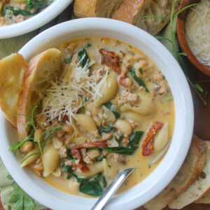 A white bowl of sausage white bean soup with pasta.