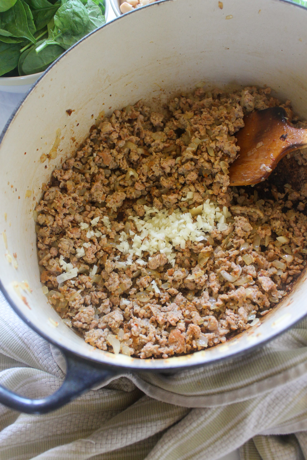 Cooked sausage in a soup pot with minced garlic.