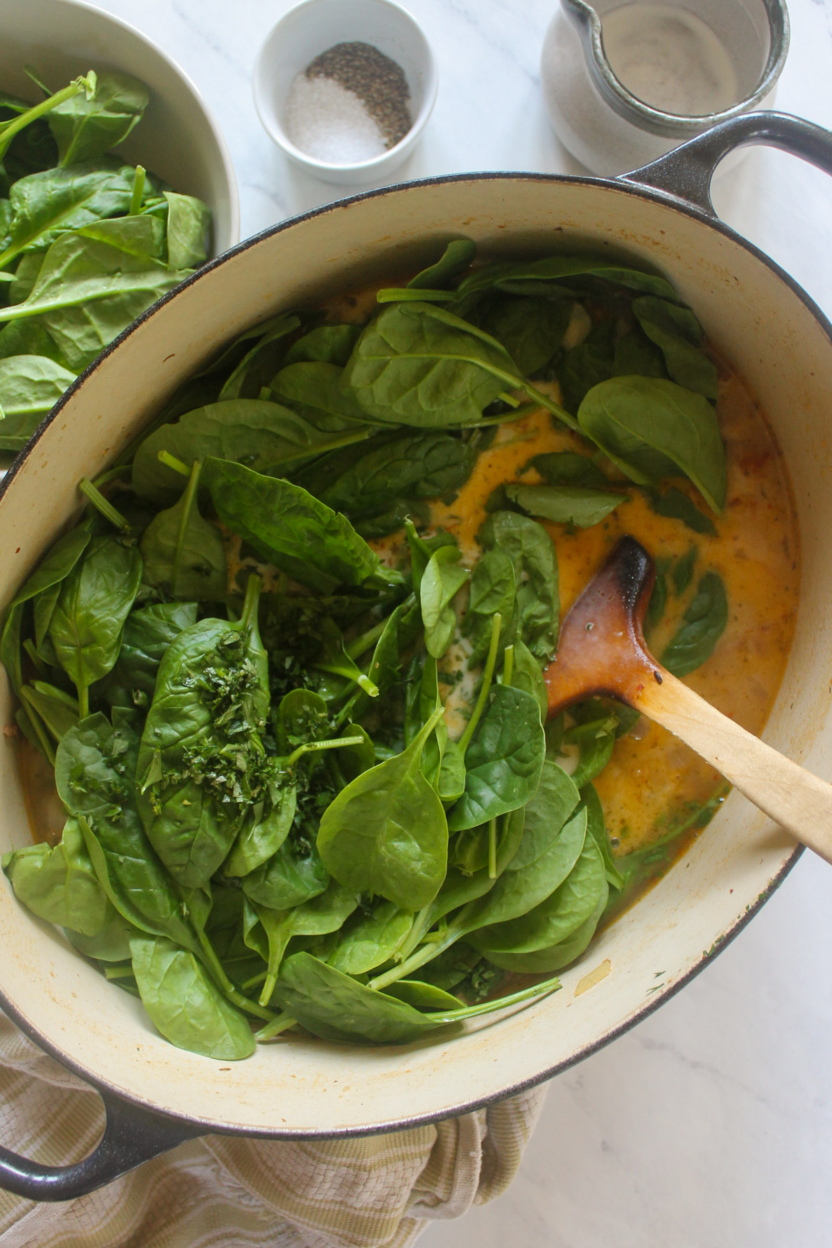 Adding lots of fresh spinach to wilt into soup.