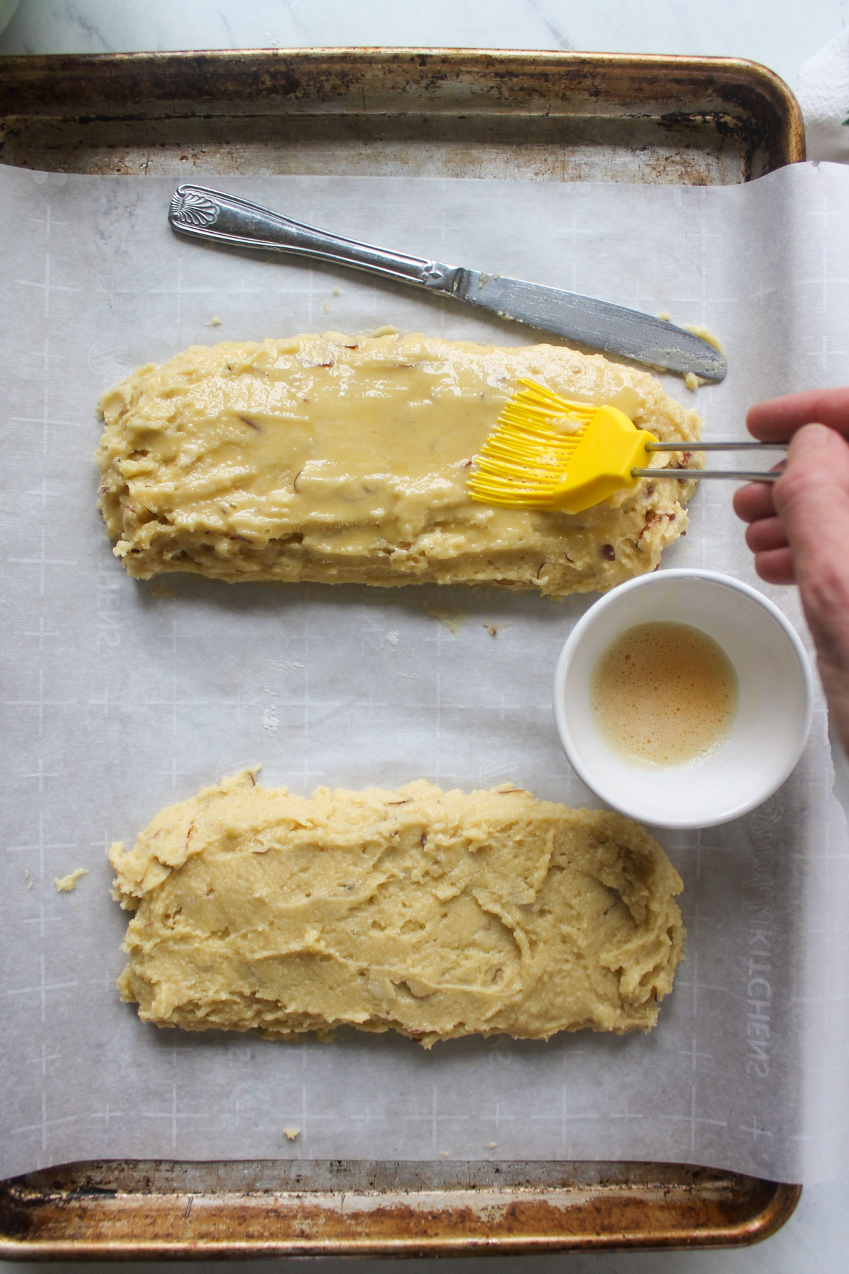 Brushing biscotti batter loaves with egg wash.