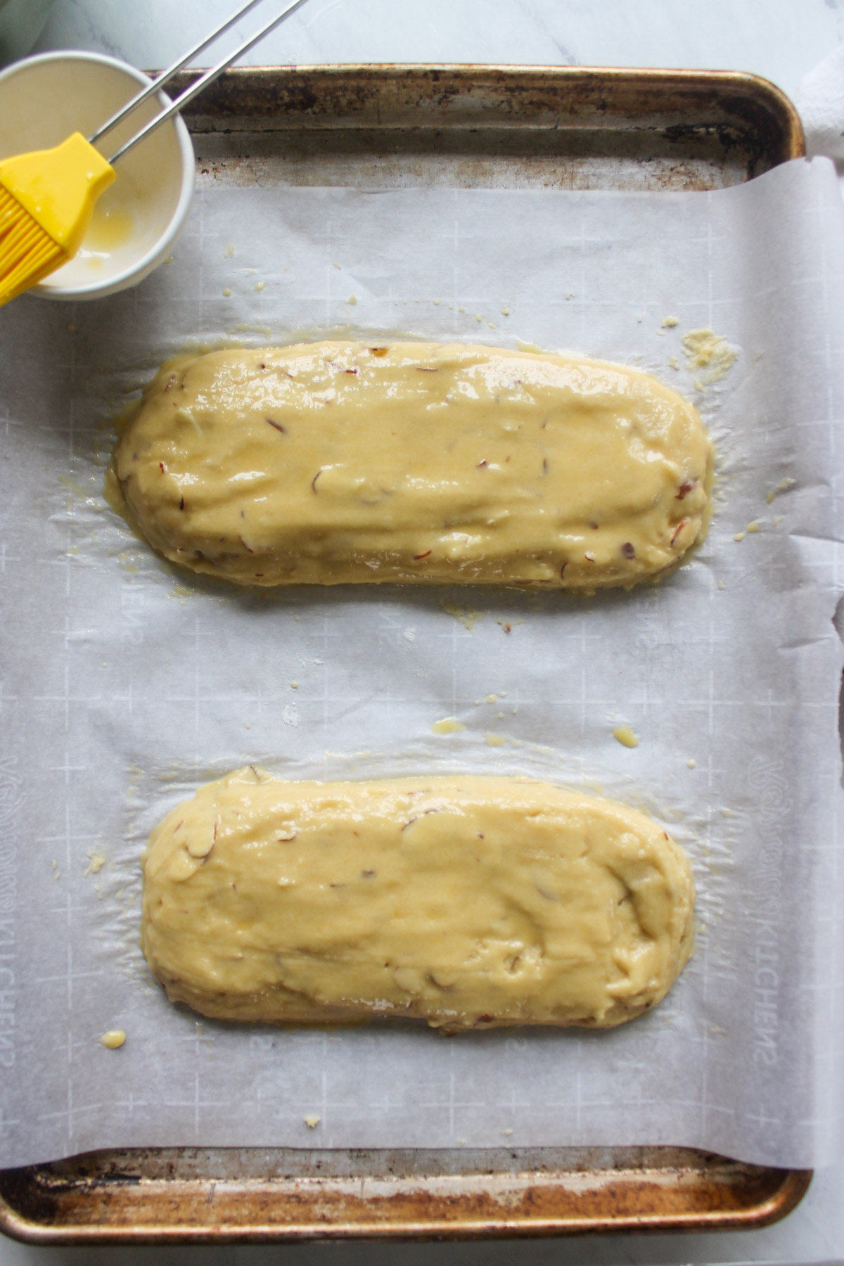 Biscotti batter on sheet pans on parchment paper ready to bake.