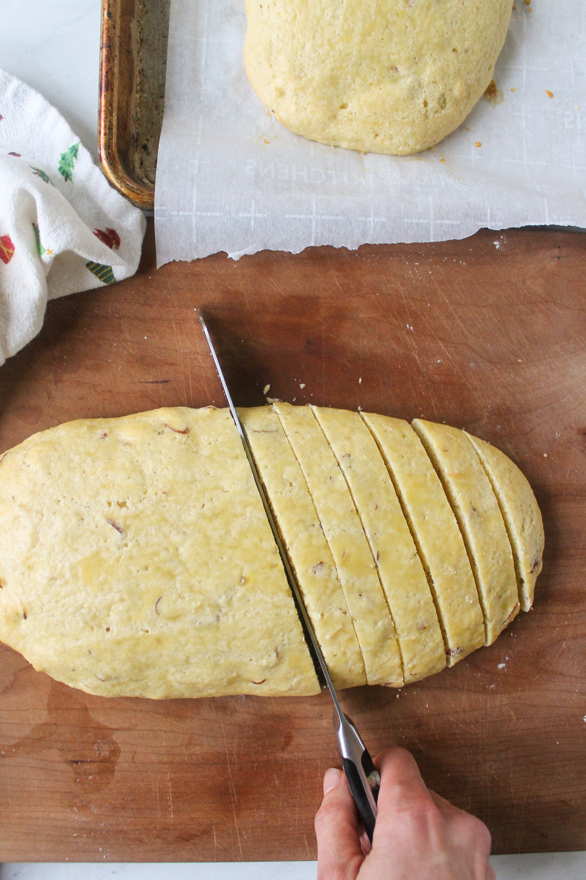 Slicing a biscotti loaf into cookies on a cutting board.