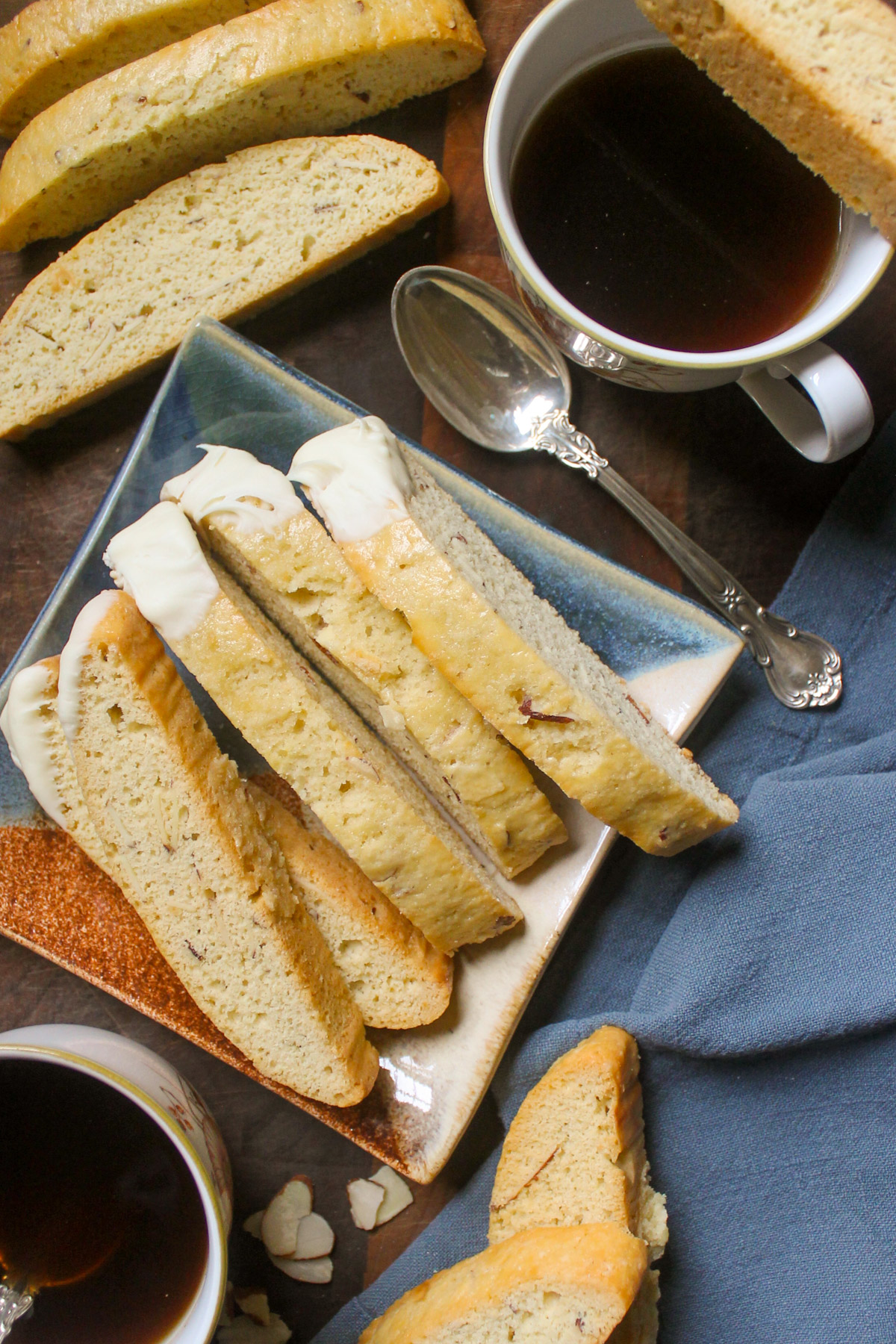 Almond biscotti on a plate with coffee and spoons.