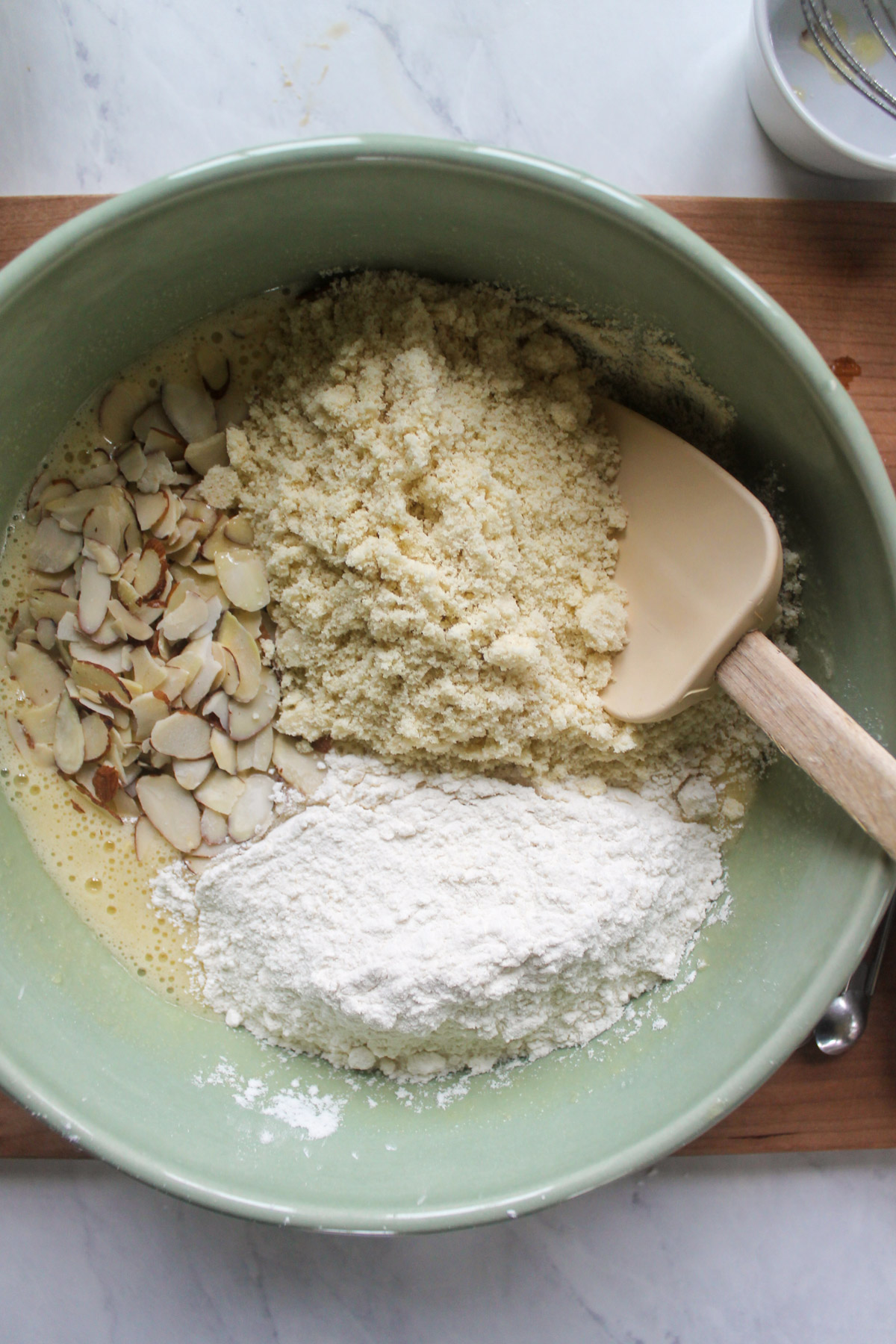 Adding flour, almond flour and almonds for biscotti batter.