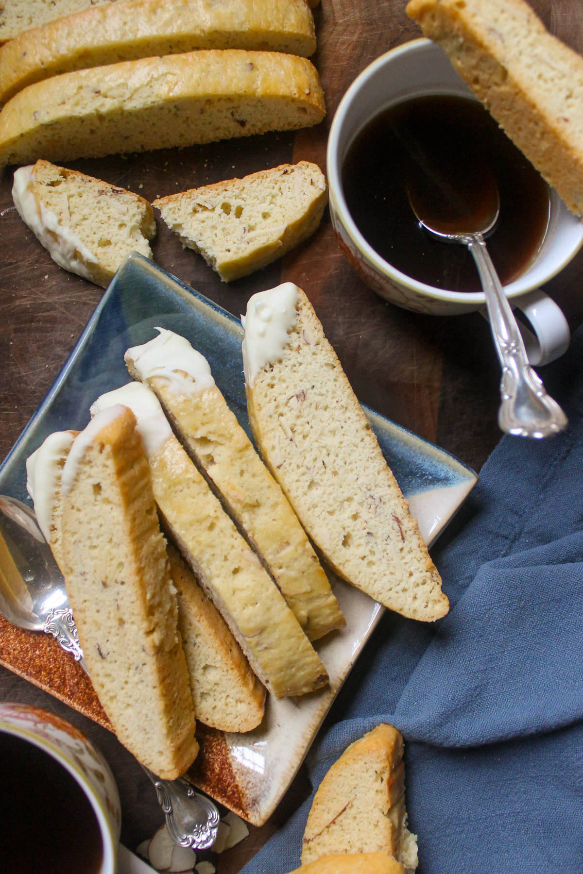 Almond biscotti cookies dipped with white chocolate on a plate with coffee.