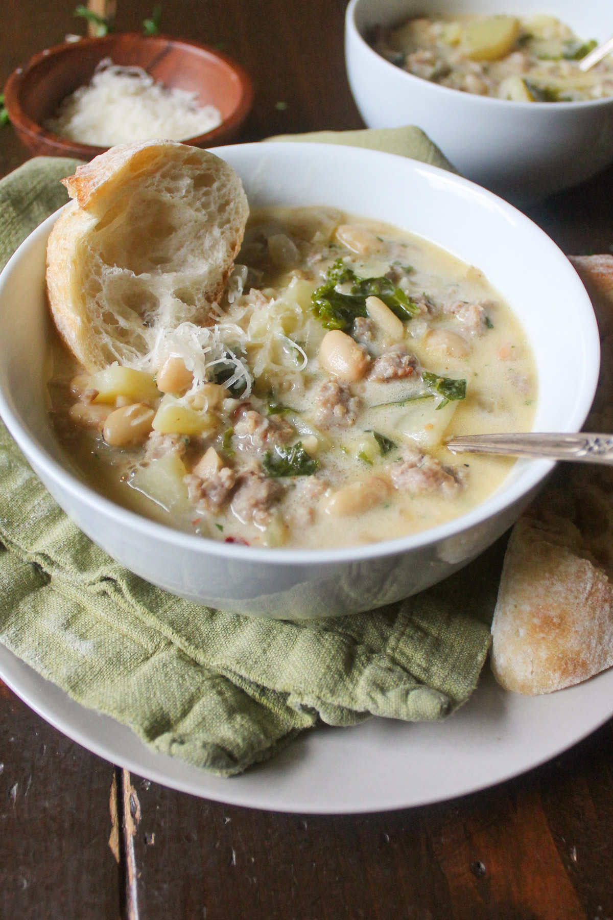 A bowl of sausage potato soup with kale.